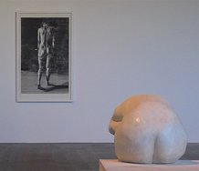 Sam Harrison: On the wall, Woman Walking Away, 2011, woodcut, 1425 x 895 mm; on plinth, Seated Woman, 2011, wax on plaster, 800 x 890 x 420 mm.