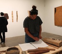 A visitor to Papakura Art Gallery examines the notebook in which Nikau Hindin has recorded her research into aute.