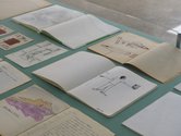 Long vitrine presenting a selection of Bill Culbert's notebooks, jotted on pages of paper and working sketches. Image courtesy of Te Uru. Photo by Sam Hartnett.   